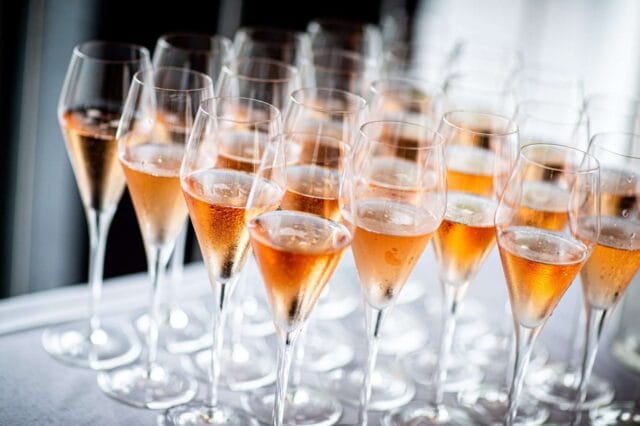 A tray of pink champagne in fluted glasses ready to be served to guests at a Winslade Manor wedding reception.