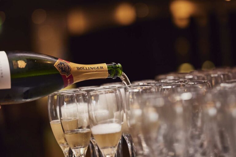 Close up image of champagne flutes being filled from a bottle of Bollinger champagne for an event at The Forge, Winslade Manor